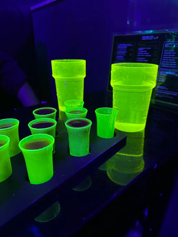 Neongrün leuchtende Shotgläser und Becher unter Schwarzlicht